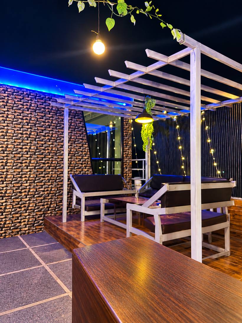 Rooftop lounge seating under a pergola at night
